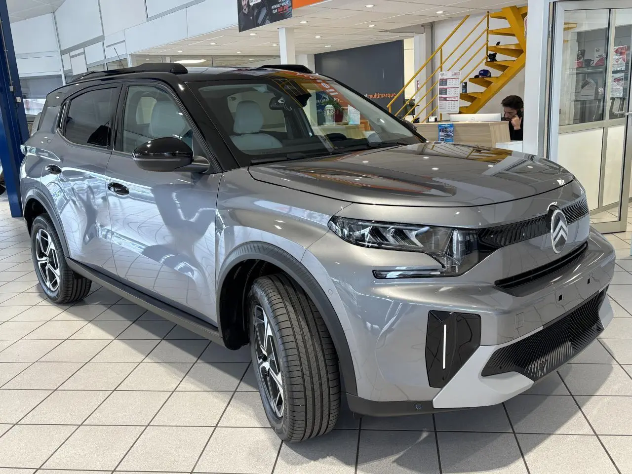 Vue 3/4 avant d'un Citroën C3 Aircross 2026 gris métallisé avec toit noir et jantes alliage 17 pouces.