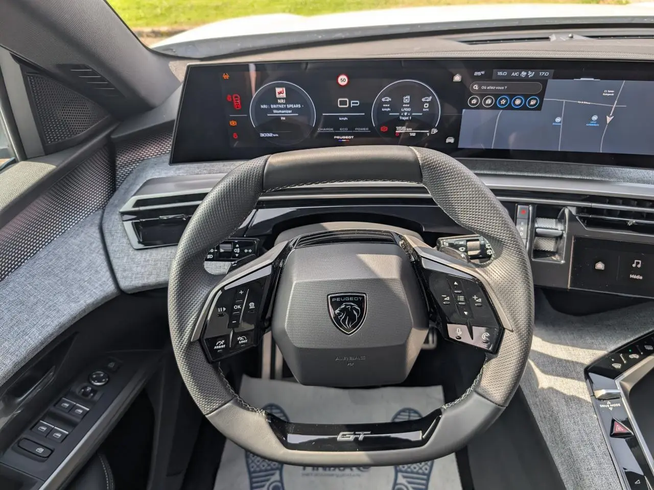 Vue intérieure centrée sur le volant compact noir GT et l'écran numérique panoramique du Peugeot 5008 blanc 2025.