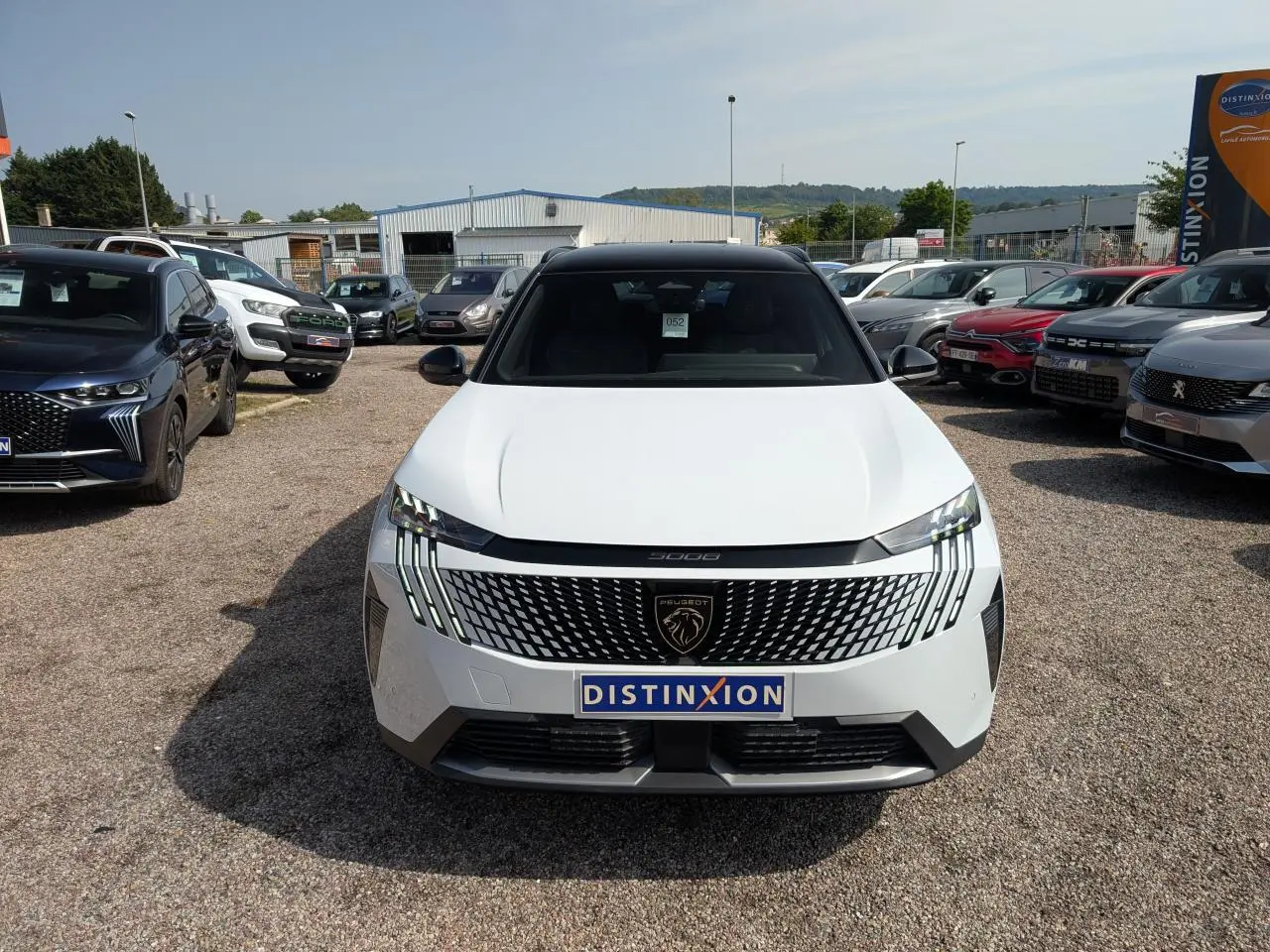 Vue avant d'un Peugeot 5008 blanc 2025 avec calandre noire à motifs et feux LED griffés, toit noir brillant.