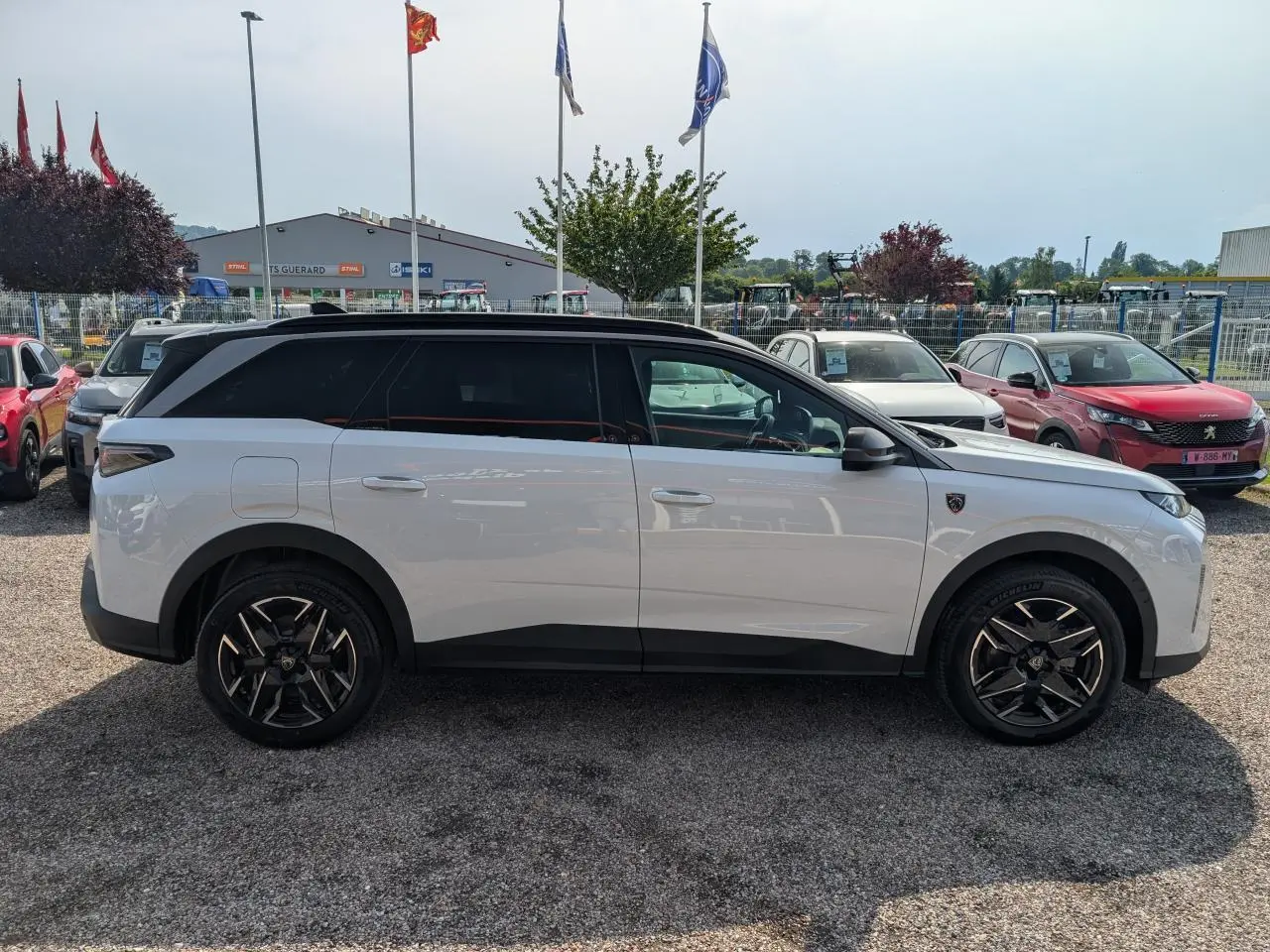 Vue de profil côté gauche d’un Peugeot 5008 blanc 2025 avec toit noir et jantes alliage noires diamantées.