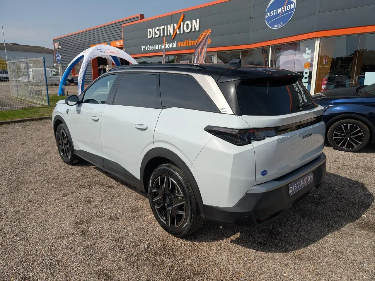 Peugeot 5008 blanc vue 3/4 arrière droit, toit noir, jantes alliage noires et feux arrière LED 3 griffes.