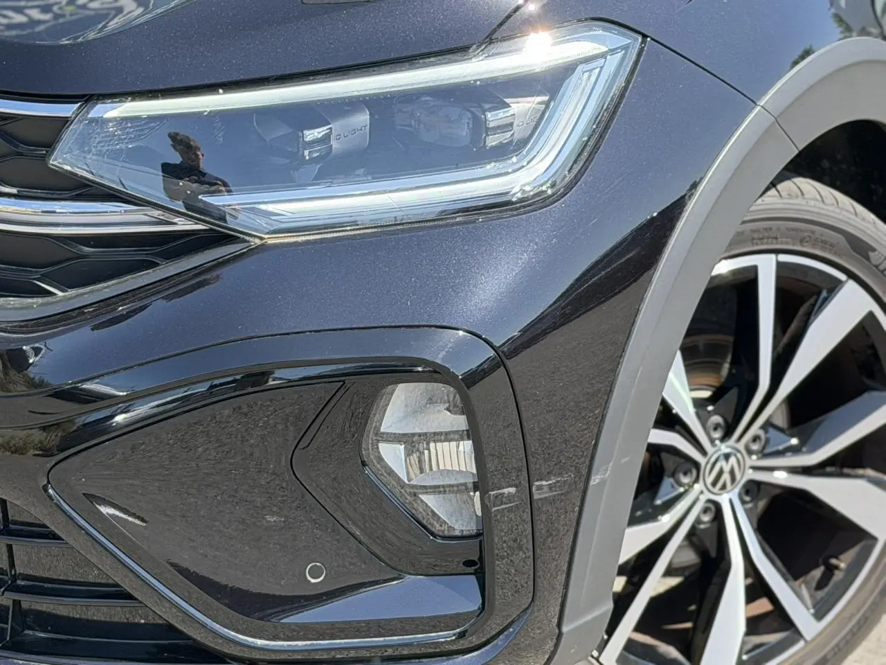 Gros plan sur l'avant droit noir métallisé du Volkswagen Taigo R-Line, mettant en valeur le phare Matrix LED et la jante 18 pouces.