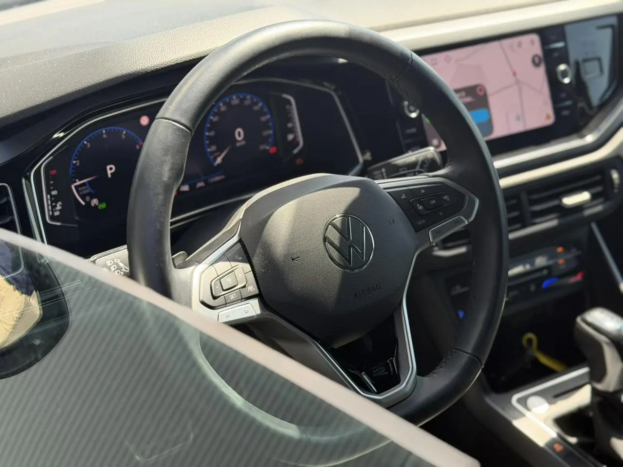 Vue intérieure centrée sur le volant cuir multifonctions et le tableau de bord digital du Volkswagen Taigo noir 2025.