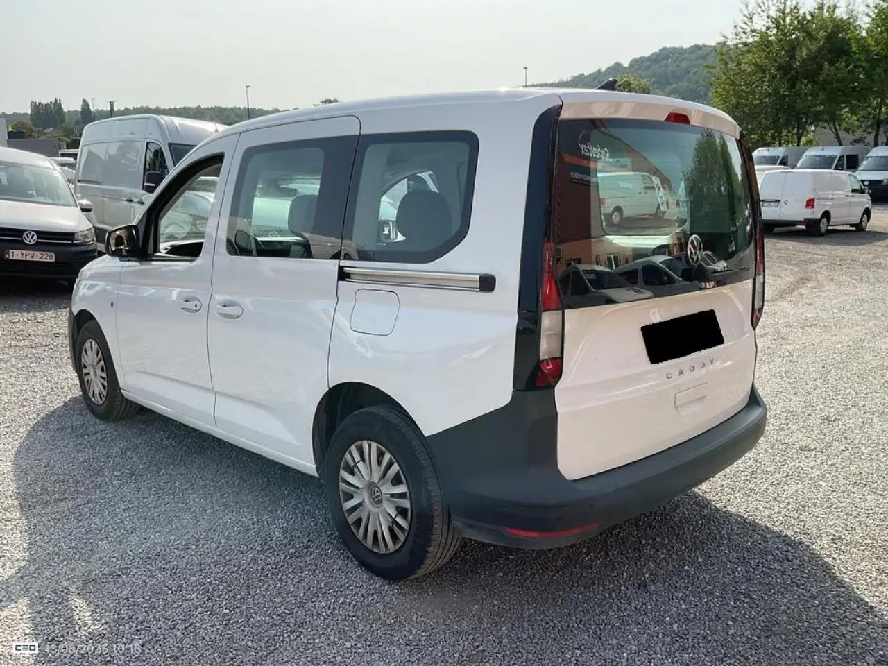 Vue 3/4 arrière droite d'un Volkswagen Caddy blanc Candy 2024 avec hayon vitré et portes coulissantes.