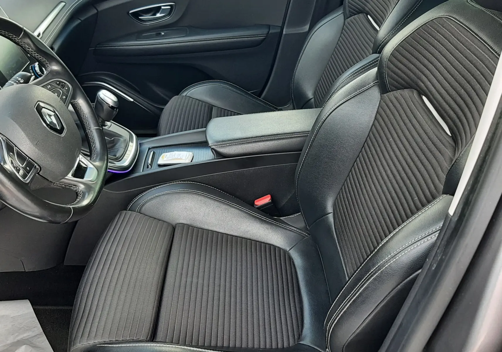 Vue intérieure du poste de conduite du Renault Scénic IV 1.7 Blue dCi, volant cuir noir et console centrale avec boîte manuelle.