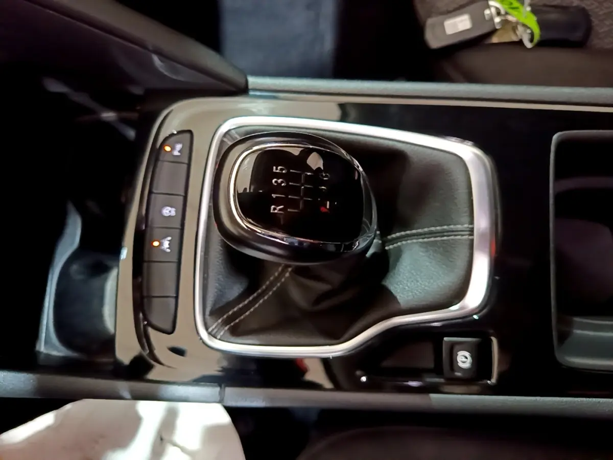 Gros plan sur levier de vitesses manuel noir et chrome dans console centrale d’Opel Insignia 2019, intérieur sombre.