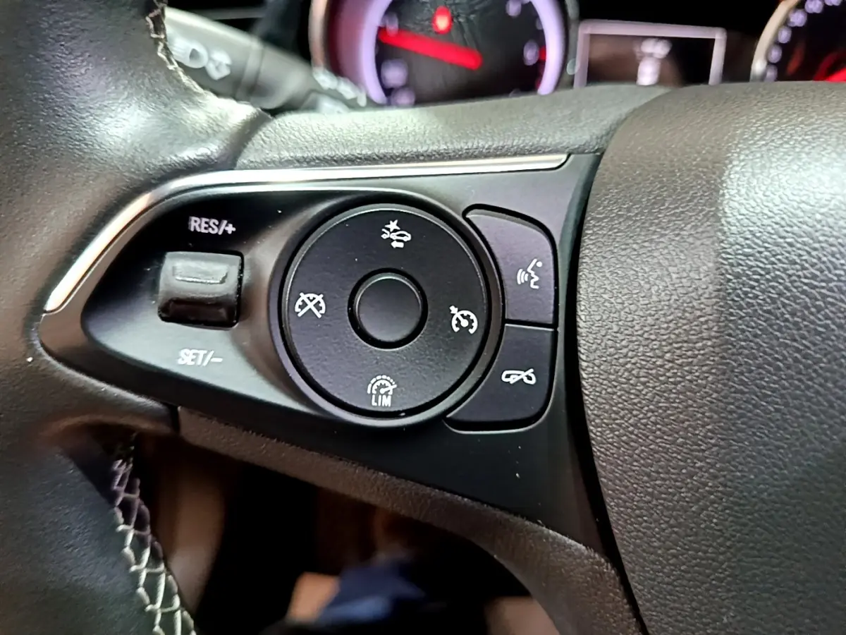 Gros plan sur les commandes du volant noir de l’Opel Insignia 2019, avec boutons de régulateur et assistant de conduite.