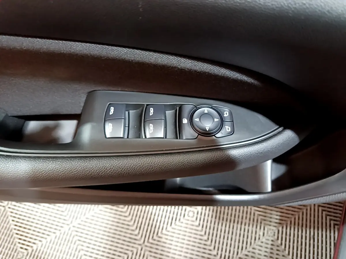 Détail des commandes de lève-vitres et rétroviseurs sur la porte côté gauche d’une Opel Insignia rouge 2019.