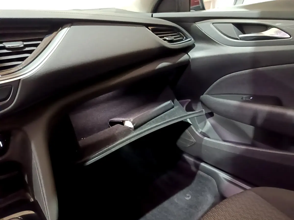 Vue intérieure côté passager de l'Opel Insignia 2019, boîte à gants ouverte et tableau de bord noir.