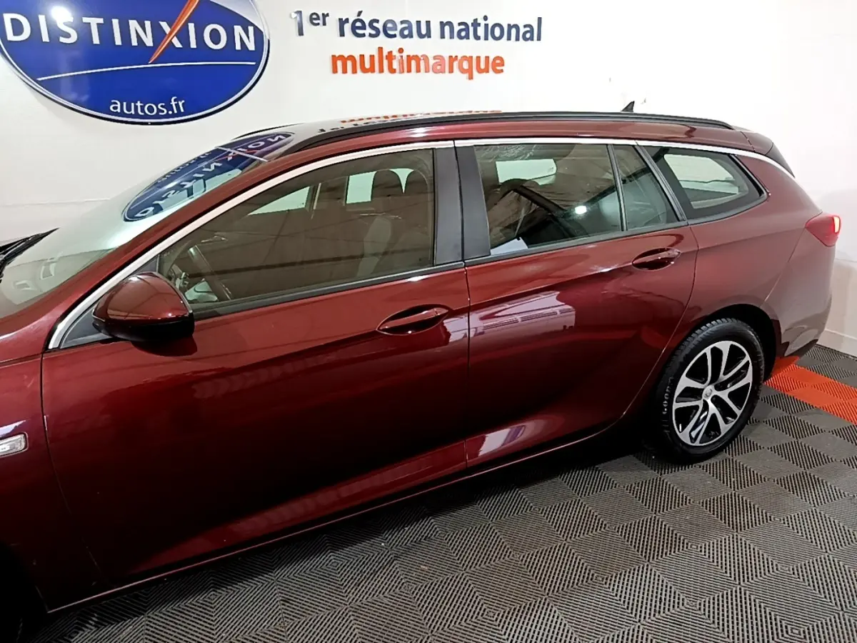 Vue latérale gauche d'une Opel Insignia break rouge 2019 avec jantes alliage et rétroviseur assorti.