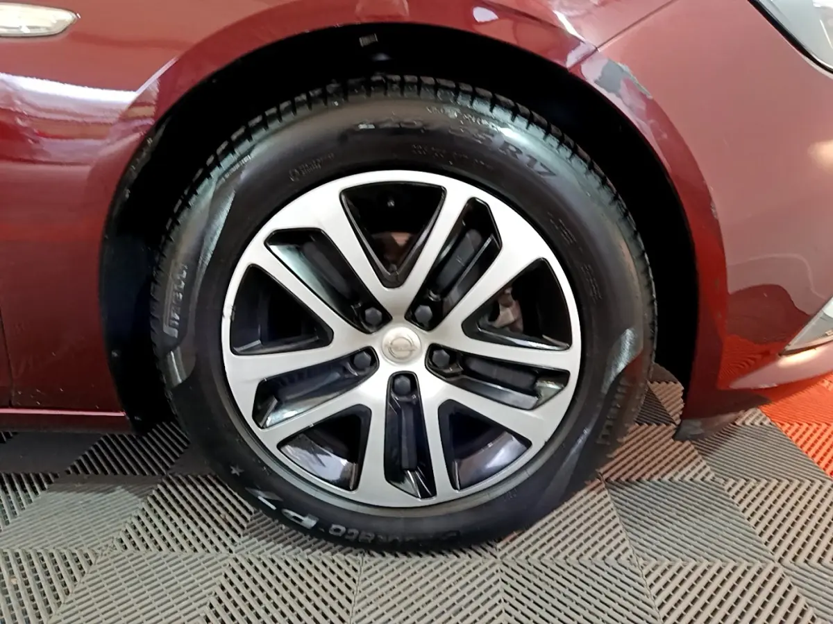 Gros plan sur la roue avant gauche d’une Opel Insignia rouge, mettant en valeur la jante alliage bicolore.