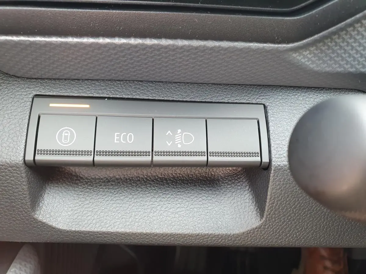 Boutons de commande du tableau de bord du Dacia Dokker Van 2026, avec mode ECO et réglage des phares visibles.