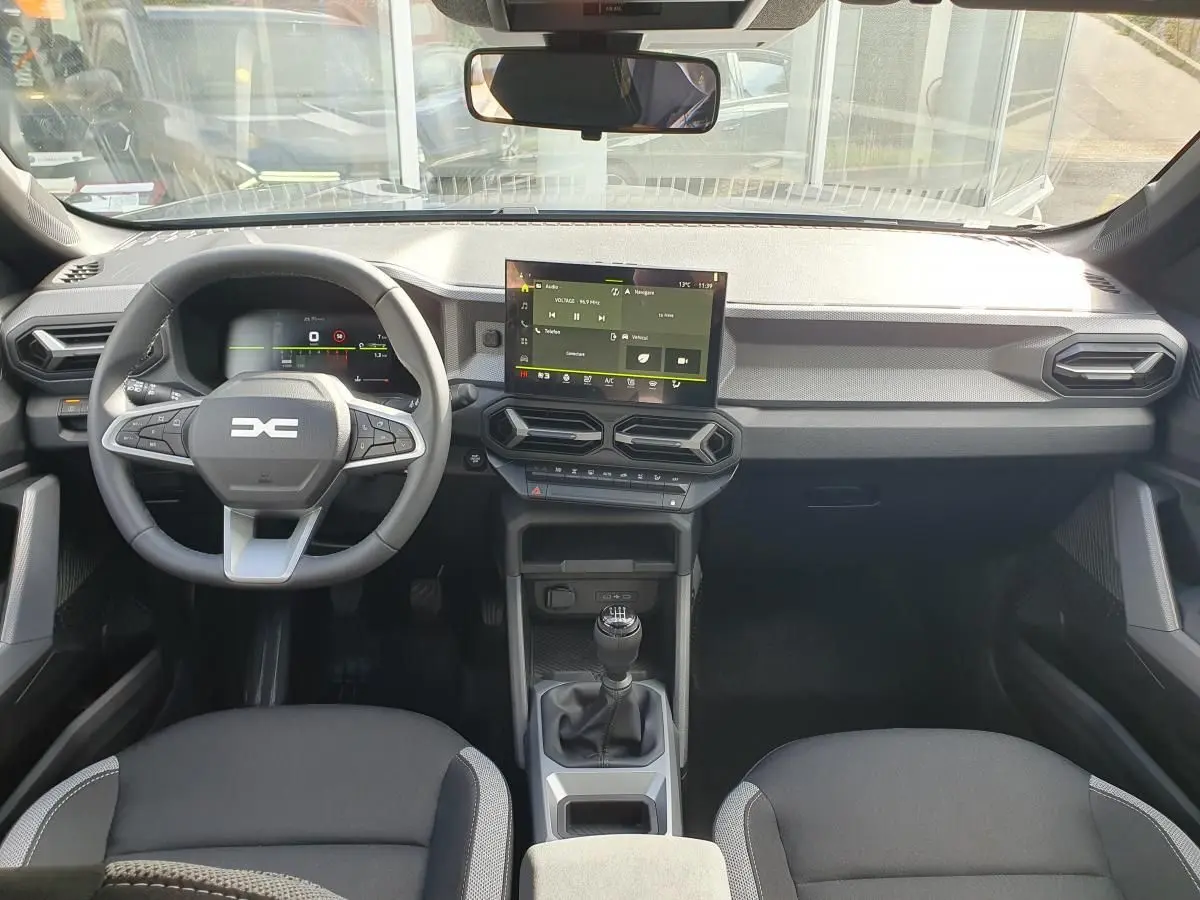Vue intérieure frontale du tableau de bord gris et noir du Dacia Dokker Van 2026 avec écran tactile et volant multifonction.