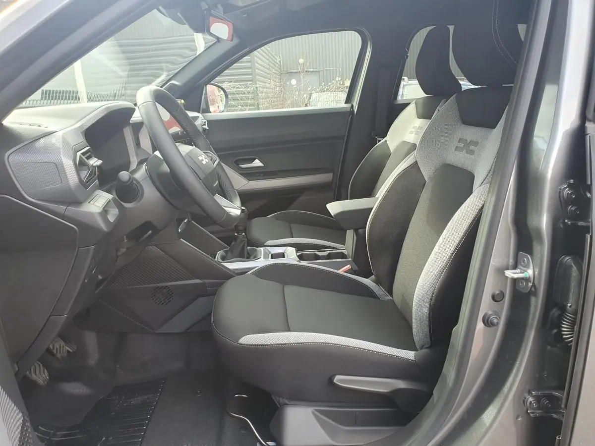 Vue intérieure côté conducteur du Dacia Dokker Van gris schiste, montrant les sièges avant et le tableau de bord.