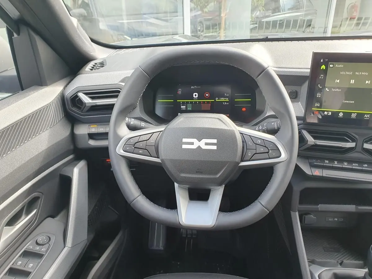 Vue intérieure centrée sur le volant et le tableau de bord numérique du Dacia Dokker Van gris schiste, avec écran tactile visible.
