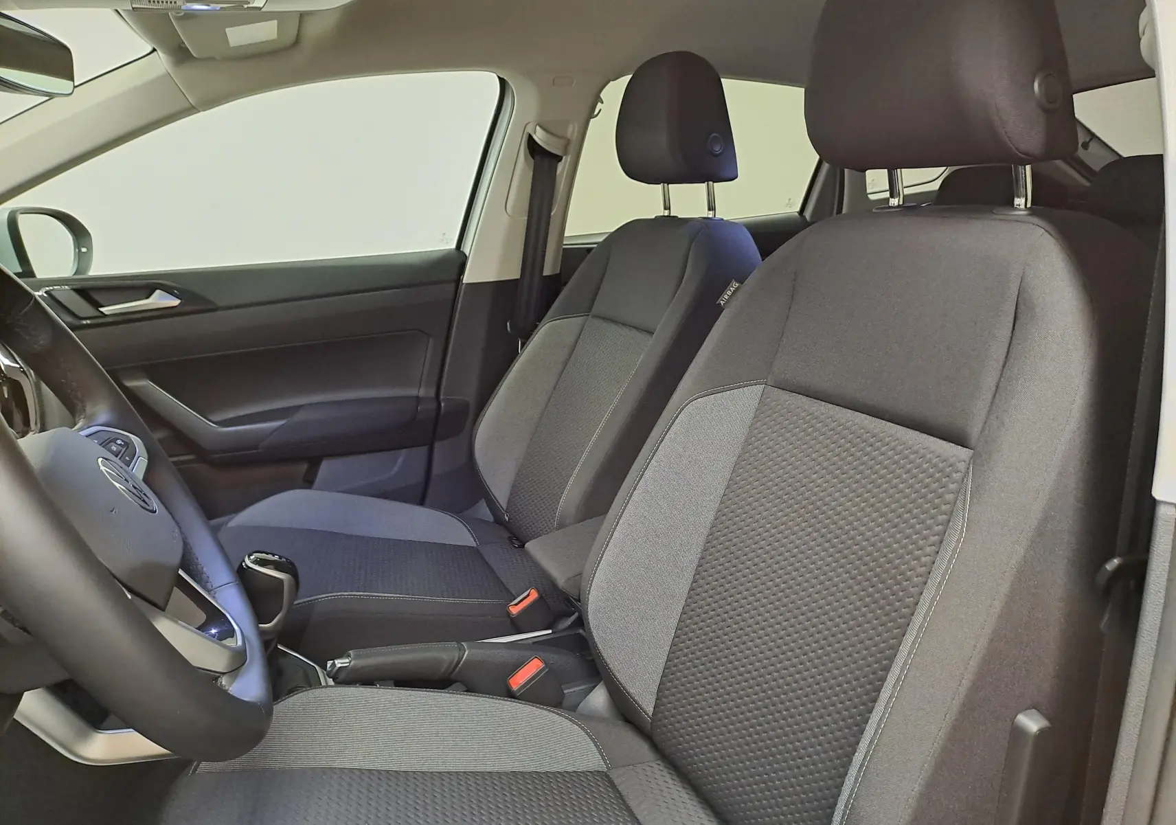 Vue intérieure côté gauche du Volkswagen Taigo 2025, sièges avant en tissu gris avec détails texturés.
