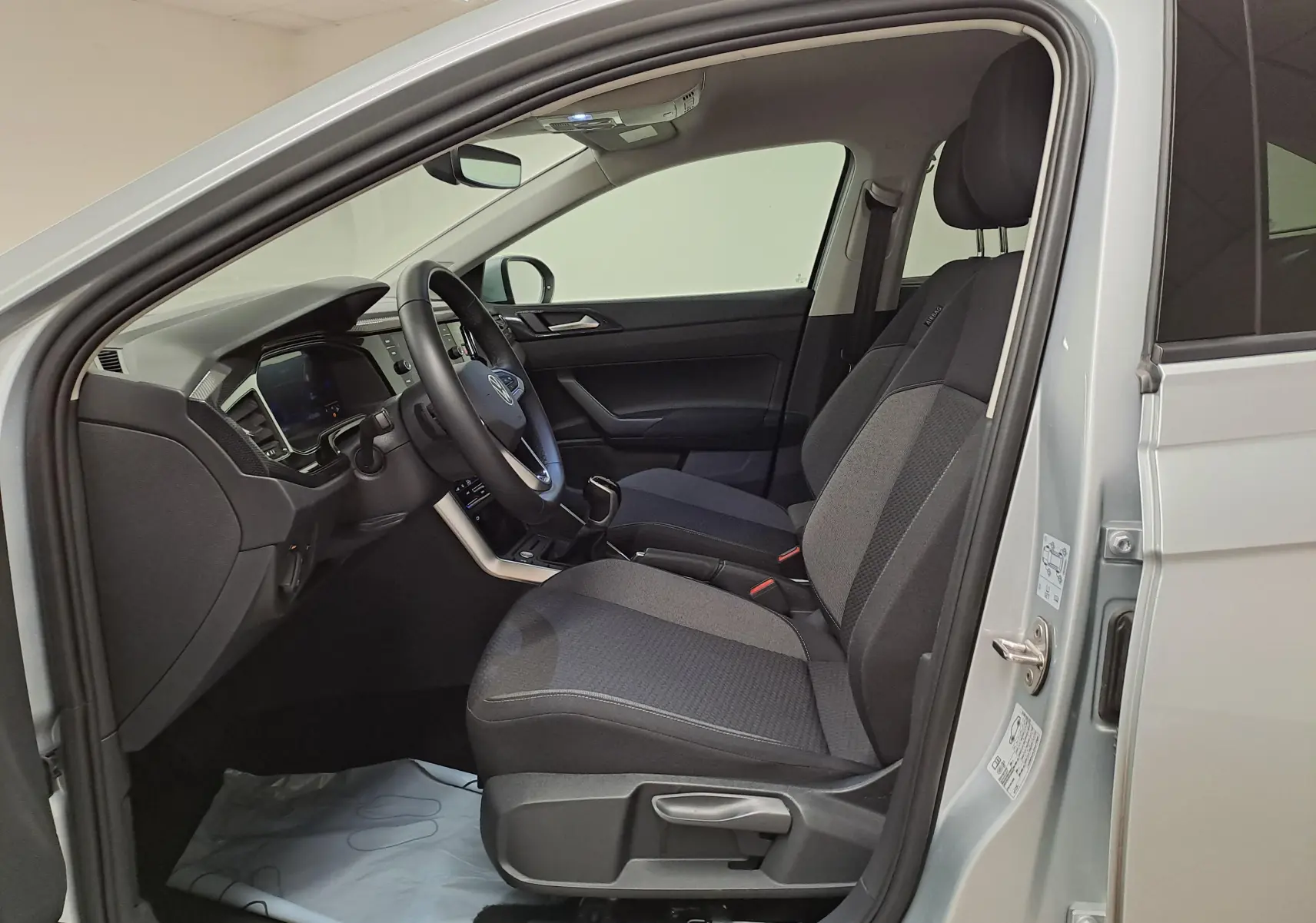 Intérieur côté conducteur du Volkswagen Taigo 2025 argent, montrant sièges tissu gris et tableau de bord moderne.