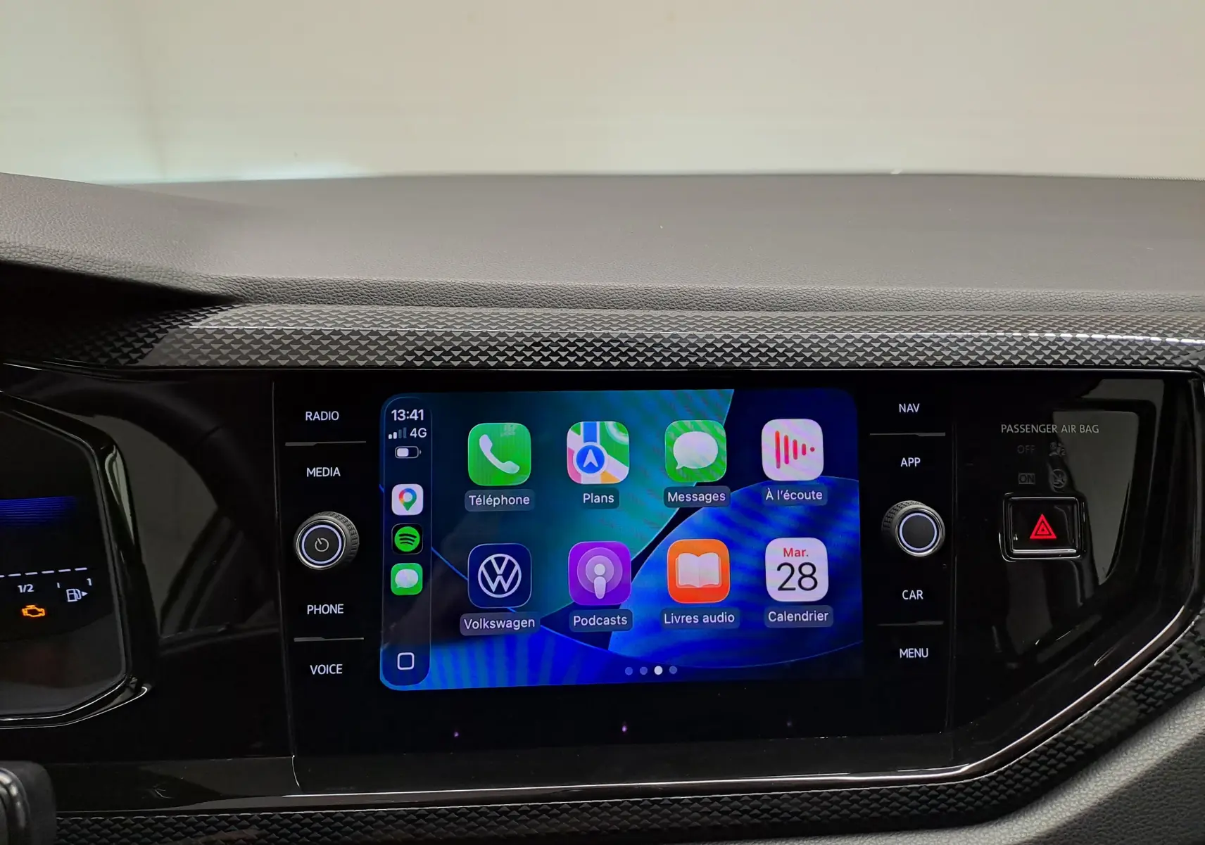 Écran tactile central du Volkswagen Taigo 2025, affichant interface connectée avec commandes autour, finition noire texturée.