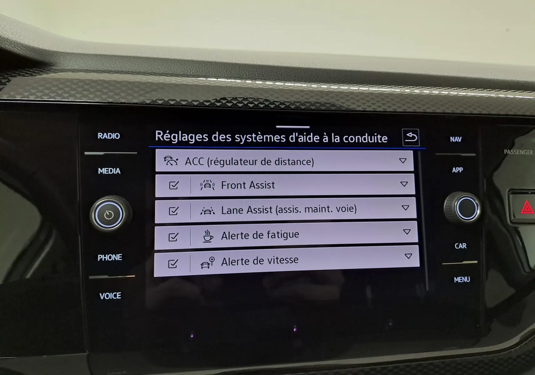 Écran tactile central du Volkswagen Taigo 2025 affichant les réglages des aides à la conduite, avec boutons autour.