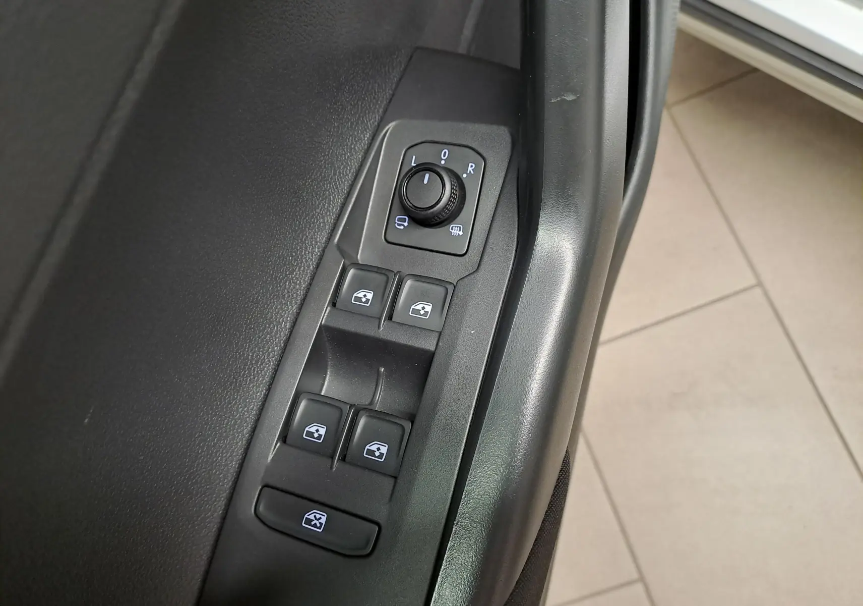 Gros plan sur les commandes de réglage des rétroviseurs et des vitres côté conducteur du Volkswagen Taigo 2025 couleur Reflet d'Argent.