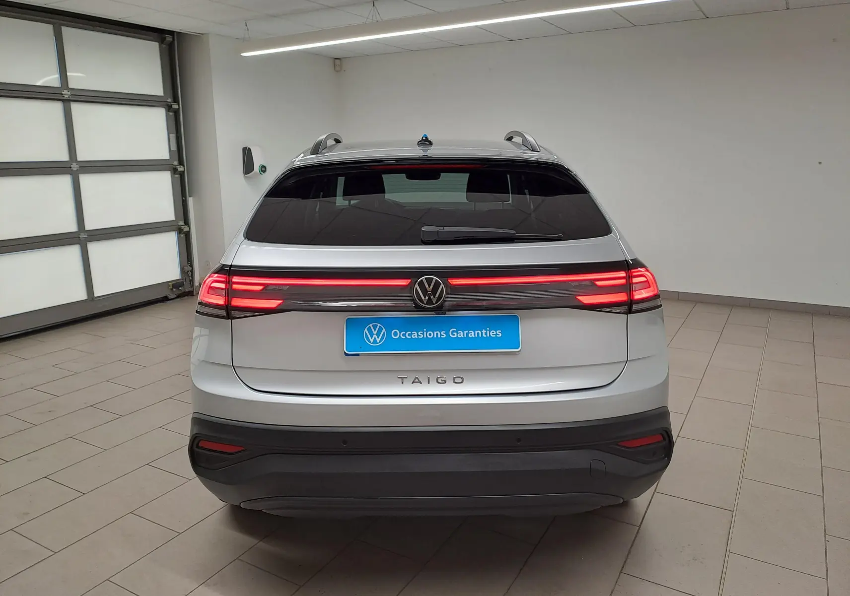 Vue arrière d'un Volkswagen Taigo 2025 en Reflet d'Argent avec feux LED allumés et toit ouvrant panoramique.