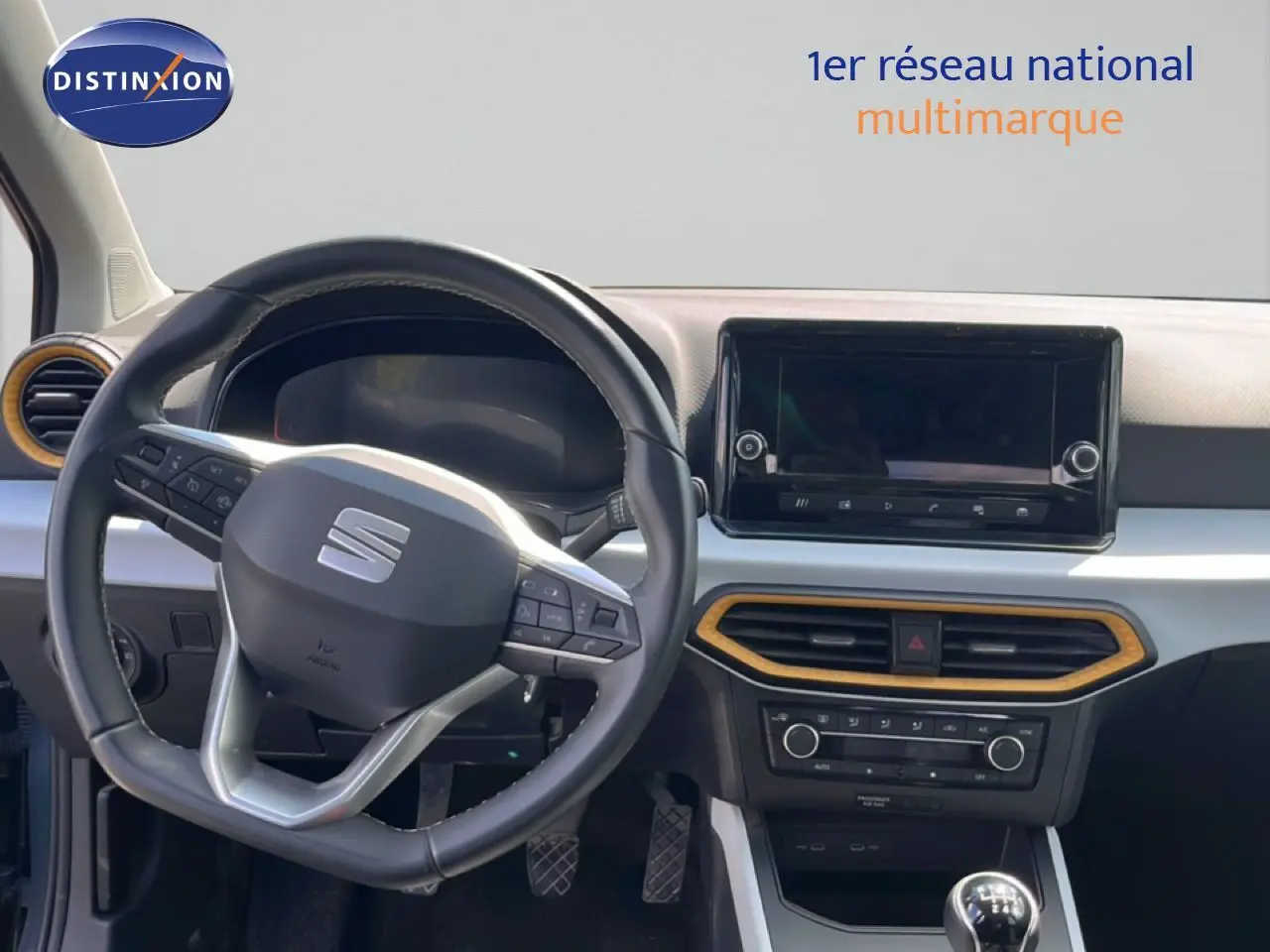 Vue intérieure du poste de conduite du SEAT Arona 2025, volant multifonction noir et tableau de bord avec écran tactile.