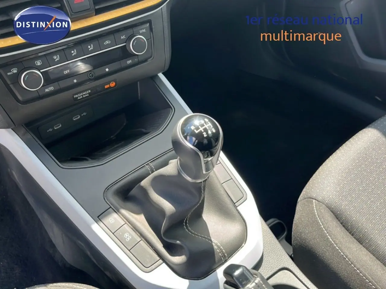 Gros plan sur la console centrale du SEAT Arona 2025 avec levier de vitesse manuel et sellerie tissu gris.