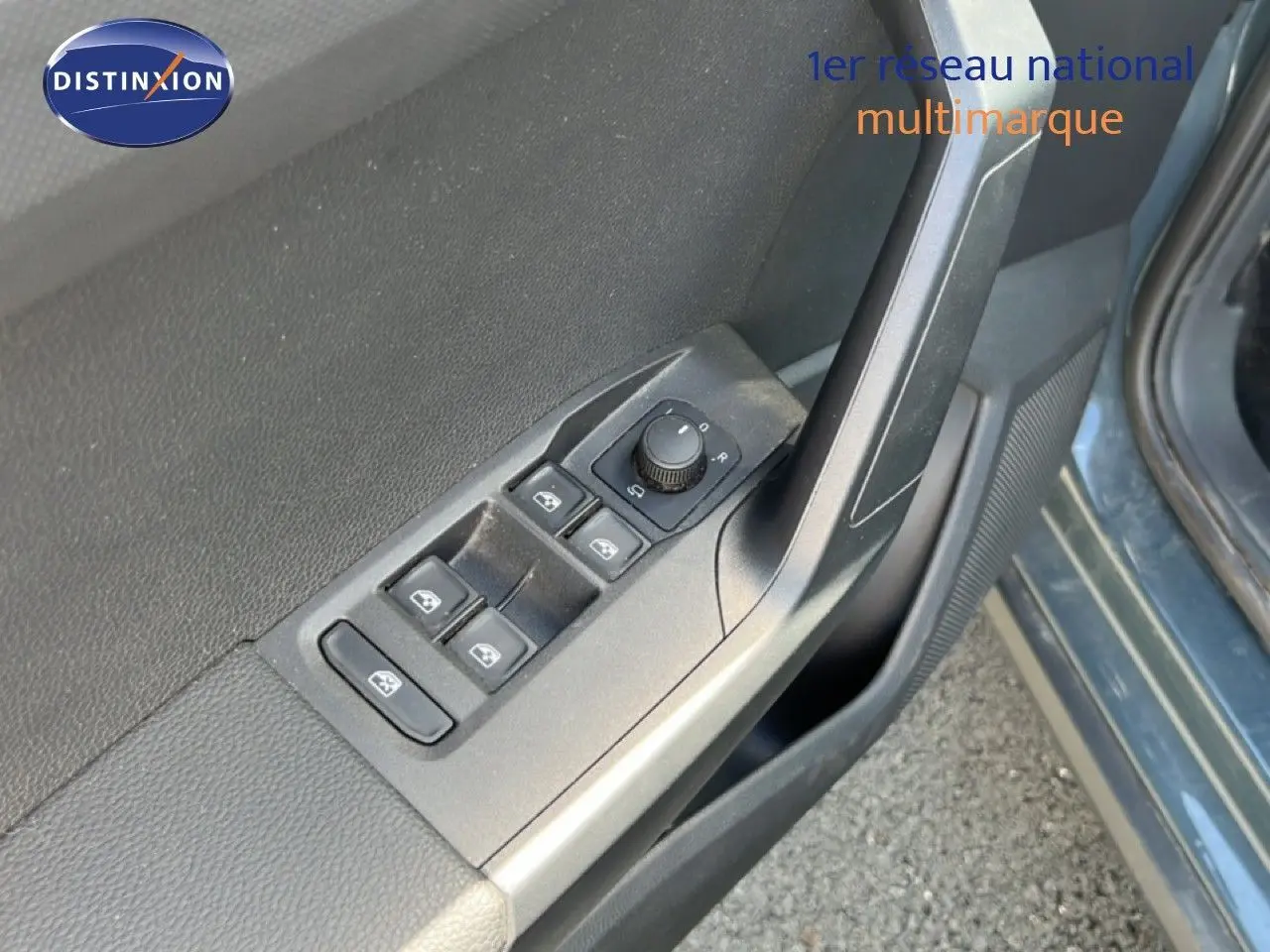 Gros plan sur les commandes de lève-vitres et réglage des rétroviseurs côté conducteur d’un SEAT Arona bleu Fjord.