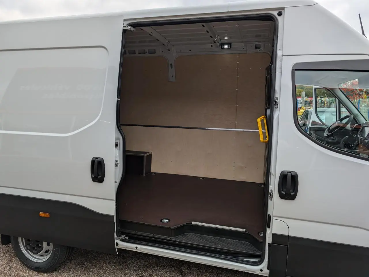 Vue latérale droite d’un Iveco Daily blanc 2025 avec porte coulissante ouverte montrant l’intérieur aménagé du compartiment de chargement.