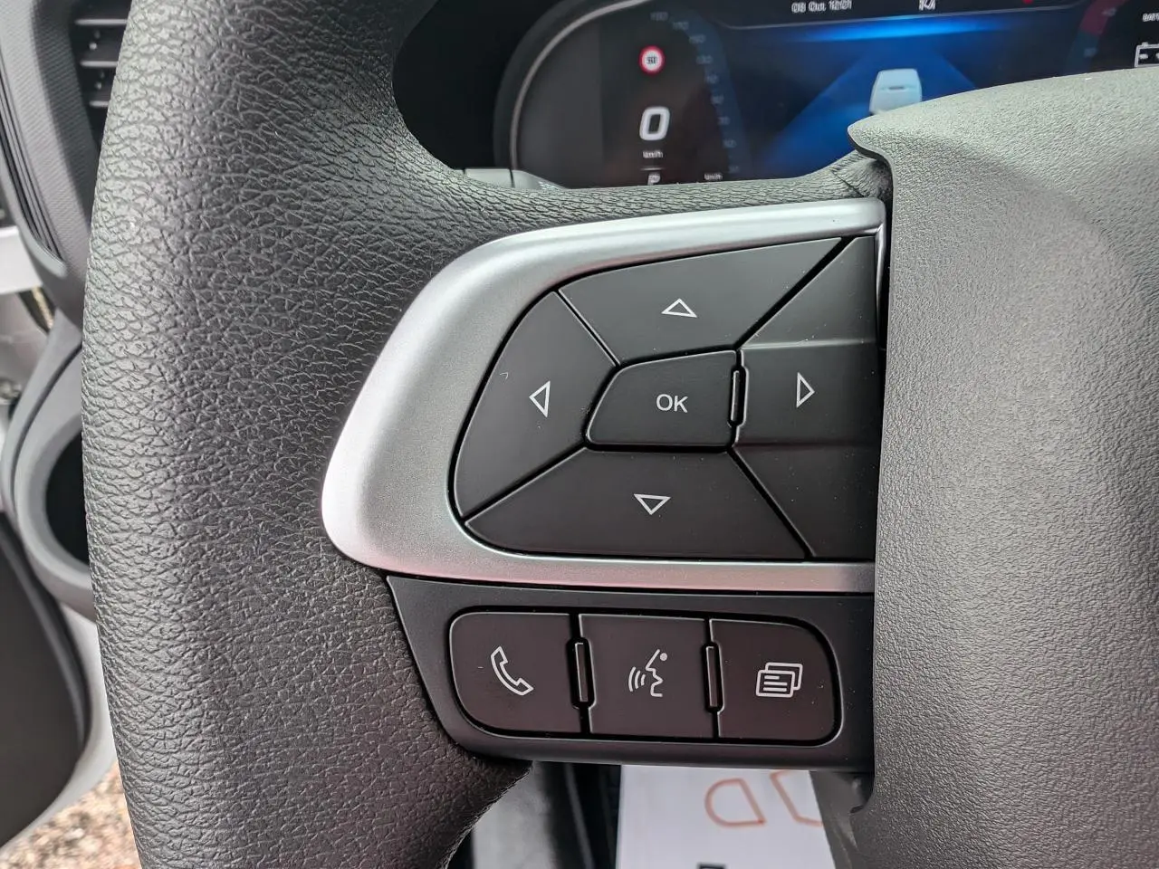 Gros plan sur les commandes multifonctions au volant du côté gauche d’un Iveco Daily blanc 2025.
