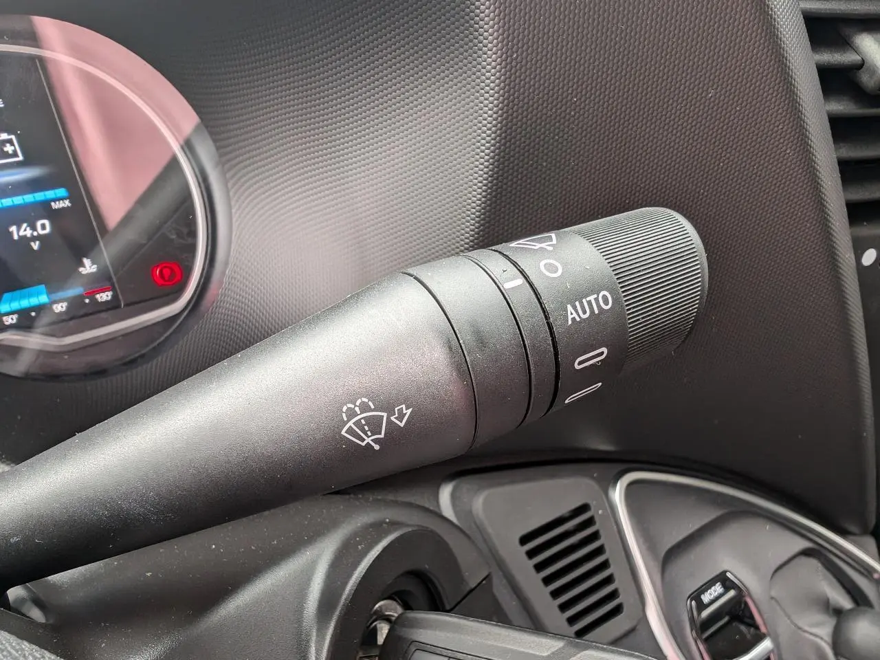 Gros plan sur la manette d’essuie-glace noire à droite du volant dans l’habitacle du Iveco Daily blanc.