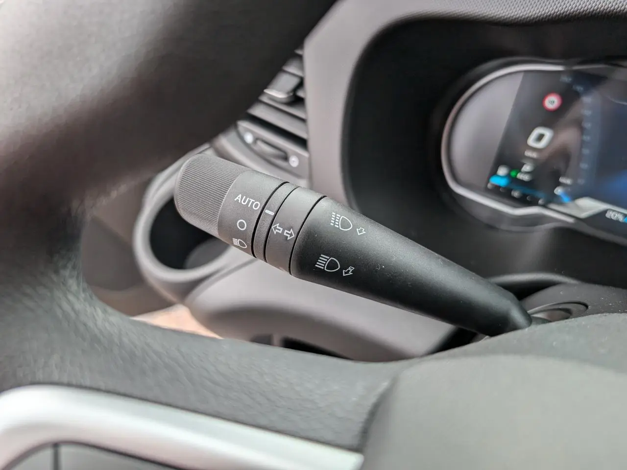 Gros plan sur la commande d’éclairage automatique noire à gauche du volant dans l’habitacle du Iveco Daily blanc.