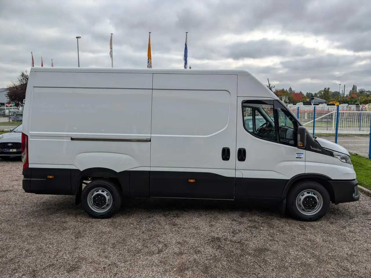 Vue de profil côté droit d’un utilitaire Iveco Daily blanc avec porte coulissante et bas de caisse noir.