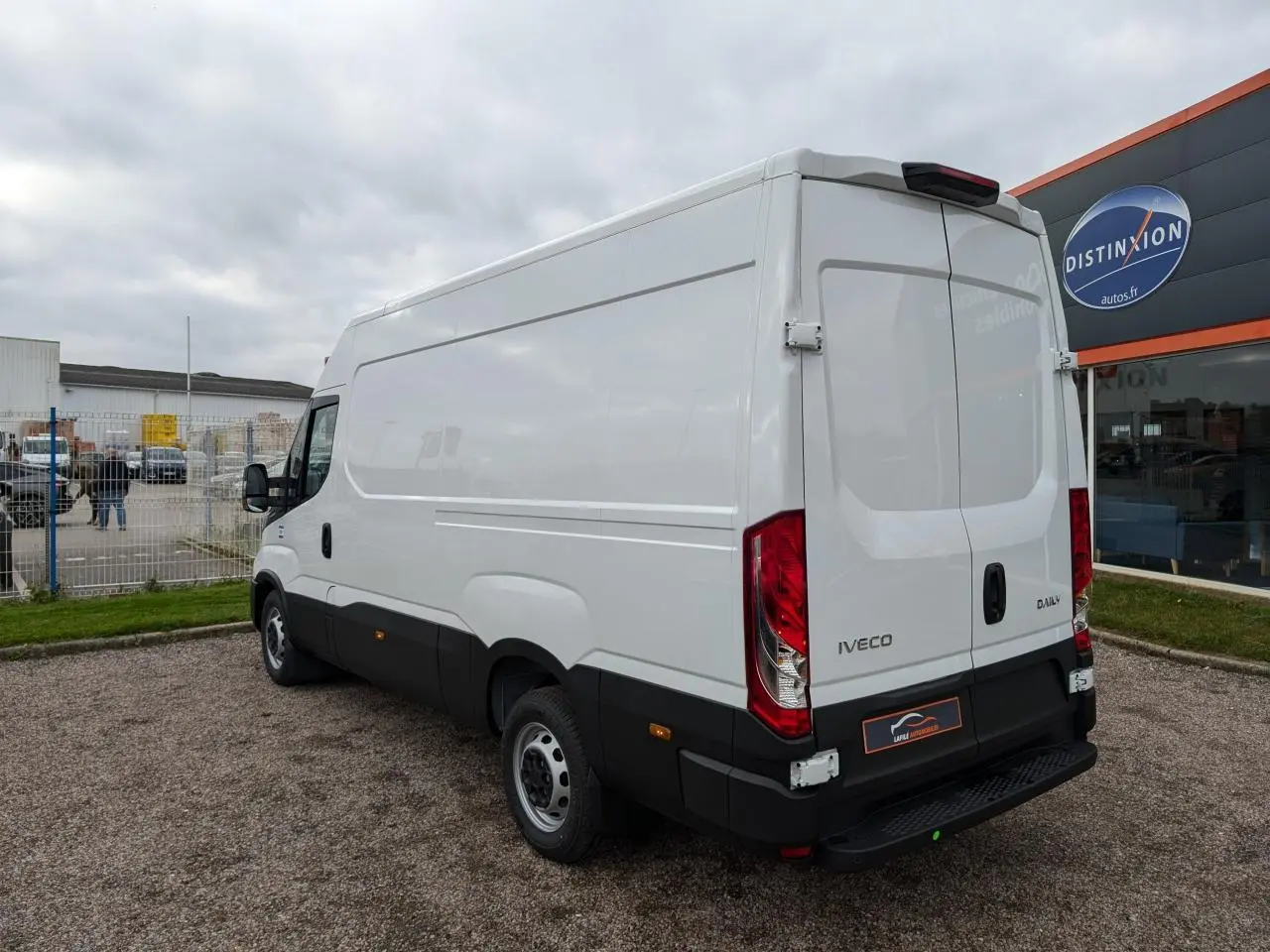 Vue 3/4 arrière droite d’un fourgon Iveco Daily blanc avec portes arrière fermées et marchepied noir visible.