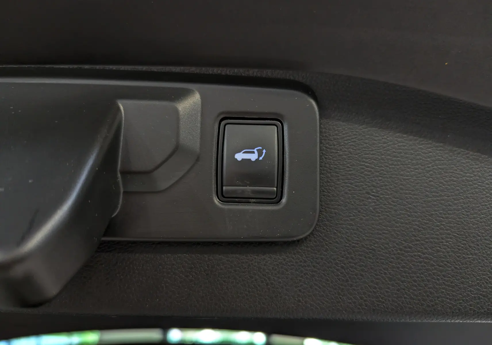 Bouton d'ouverture électrique du hayon sur la garniture intérieure d'un Renault Austral blanc nacré 2023.