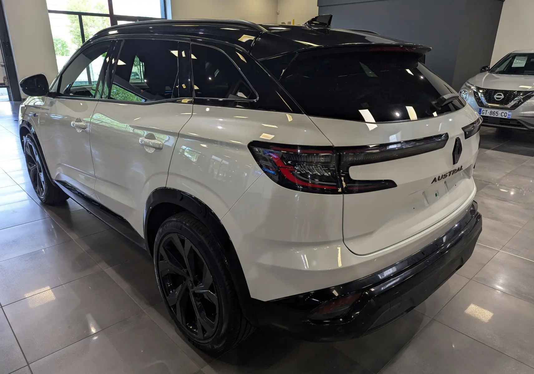 Vue 3/4 arrière droite du Renault Austral blanc nacré avec toit noir, jantes noires et feux arrière LED distinctifs.