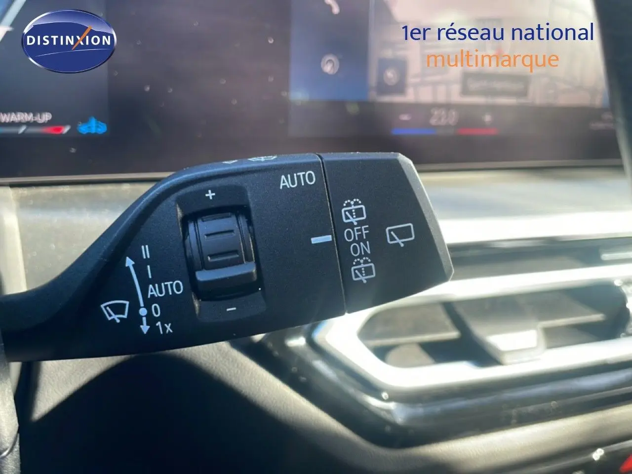 Gros plan sur la commande des essuie-glaces dans l’habitacle d’une BMW Série 3 Touring noire, avec tableau de bord flou en arrière-plan.