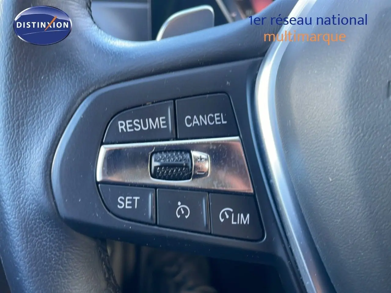 Gros plan sur les commandes de régulateur de vitesse au volant cuir noir d’une BMW Série 3 Touring F31 noir saphir.