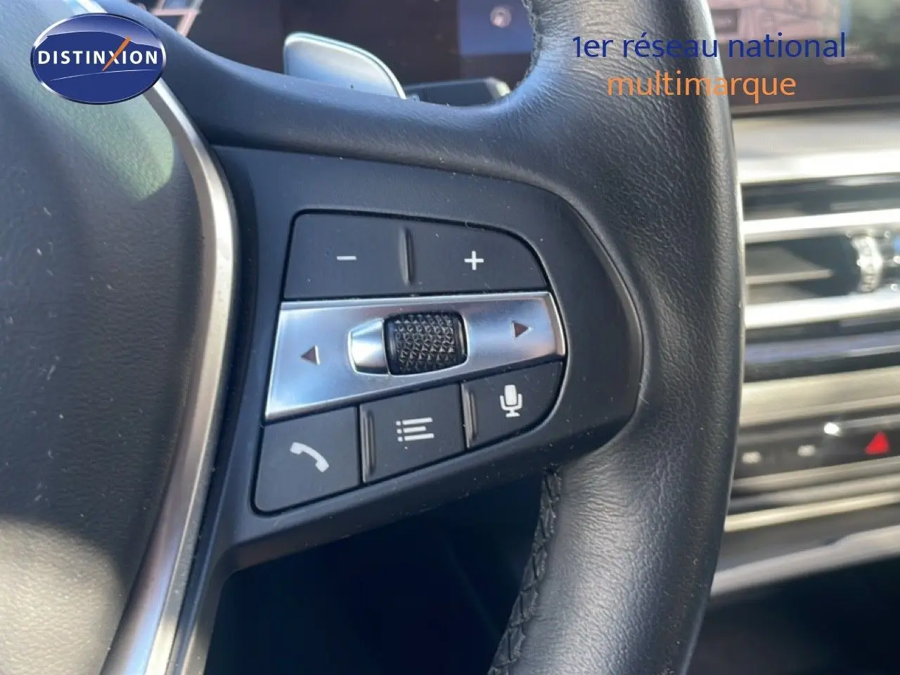 Gros plan sur les commandes du volant en cuir noir de la BMW Série 3 Touring F31 noir saphir, intérieur moderne.