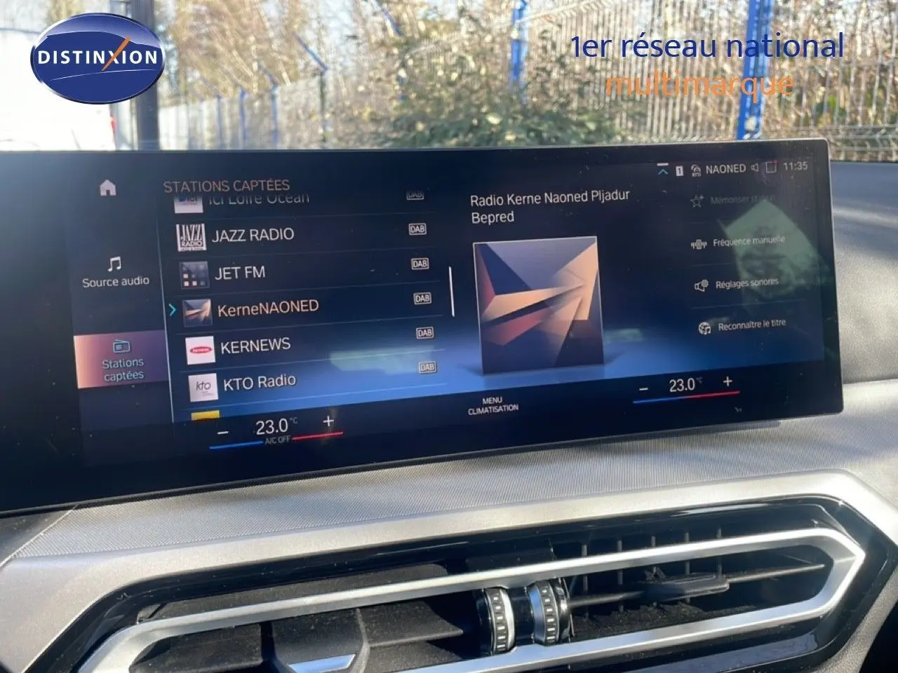 Écran tactile intérieur affichant la radio et la climatisation d'une BMW Série 3 Touring F31 noire, vue de face.