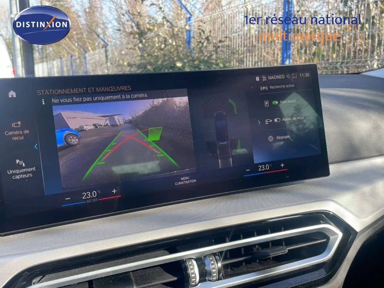 Écran central affichant la caméra de recul et l'assistance au stationnement dans une BMW Série 3 Touring noire, vue intérieure.
