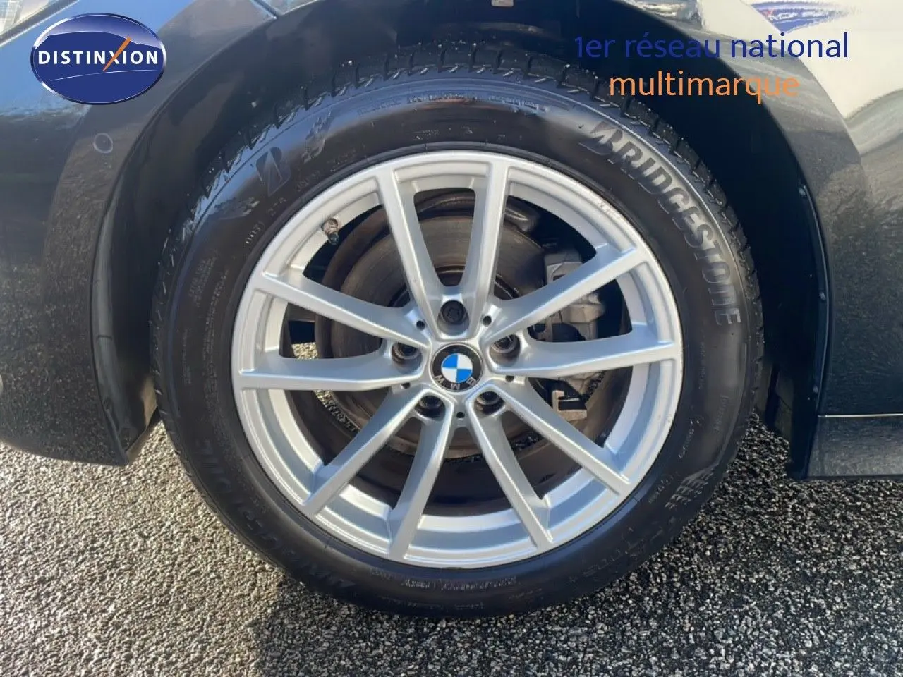 Gros plan sur la roue avant droite d’une BMW Série 3 Touring noire, avec jante alliage argent et pneu Bridgestone.