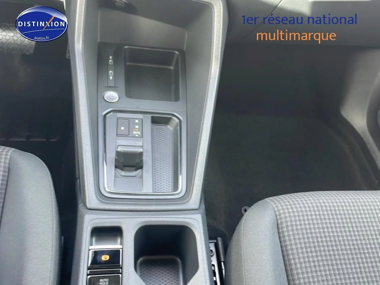 Vue plongeante sur la console centrale du Volkswagen Caddy 2025, avec levier de vitesse automatique et sièges tissu noir à motif quadrillé.