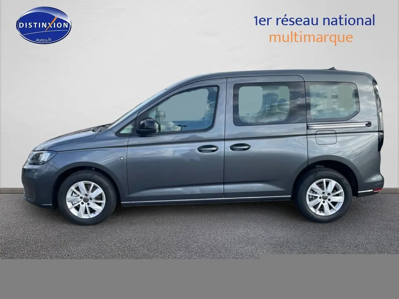 Vue de profil côté gauche d'un Volkswagen Caddy gris indien 2025 avec vitres teintées et jantes alliage.