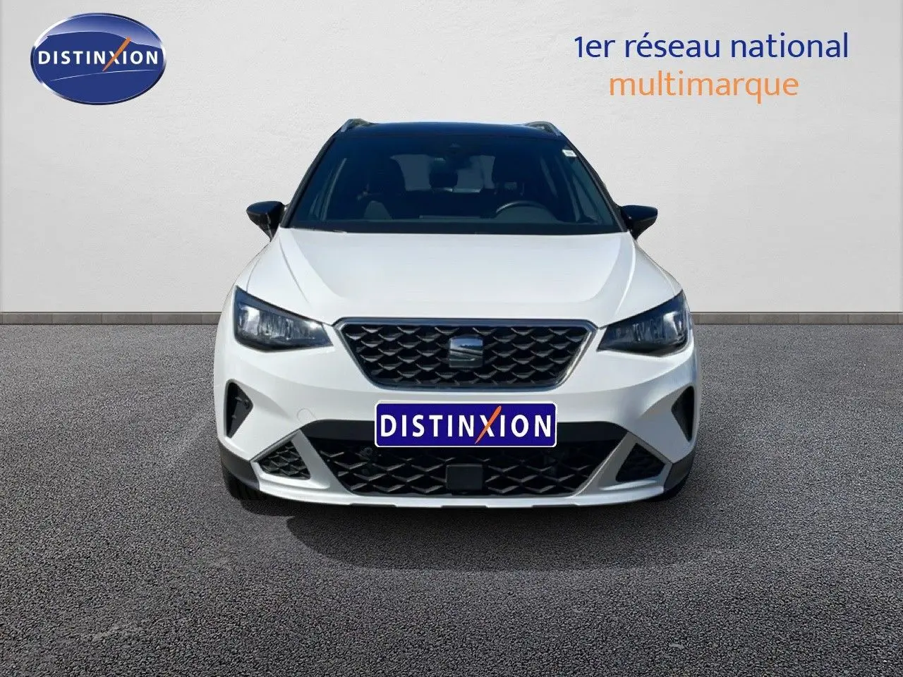 Vue frontale d'un SEAT Arona blanc Nevada avec toit noir, calandre noire et phares LED allumés.