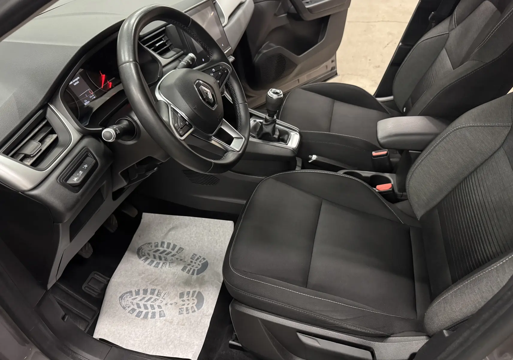 Vue intérieure côté conducteur du Renault Captur 2021, sièges noirs et volant avec commandes intégrées.