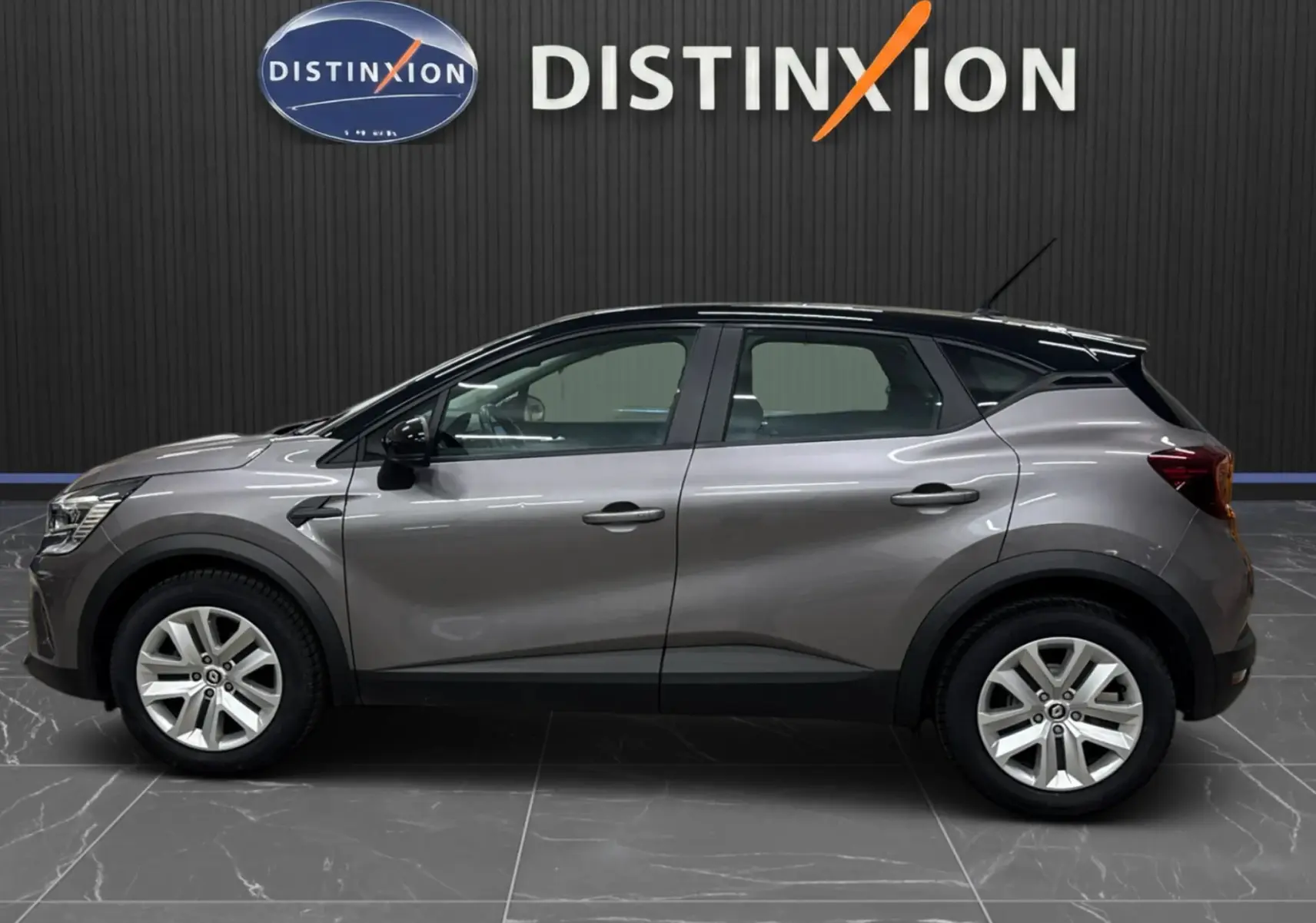 Profil droit d'un Renault Captur gris foncé avec toit noir, version TCE 90 CH BUSINESS BVM6, sur fond intérieur showroom.