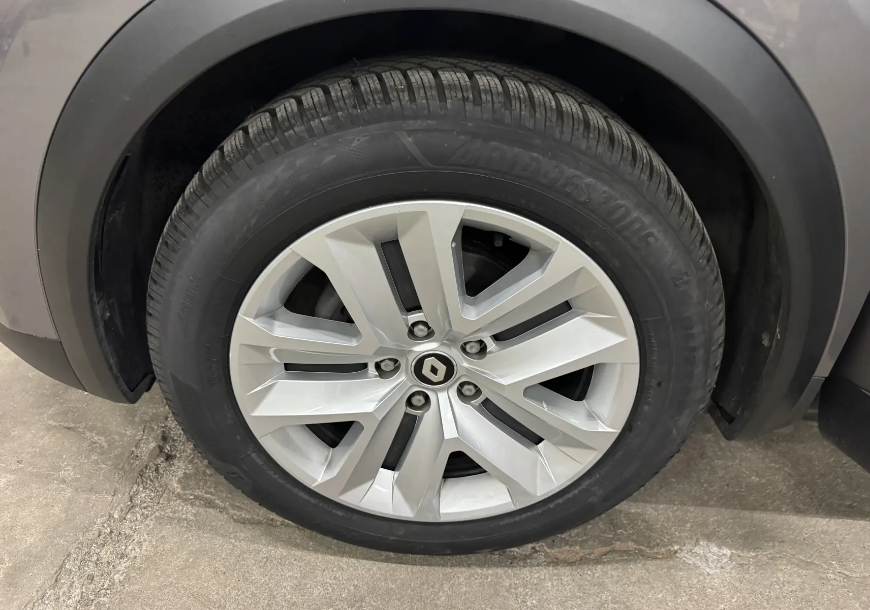 Gros plan sur la roue avant gauche du Renault Captur gris foncé, avec jante alliage et pneu Bridgestone.