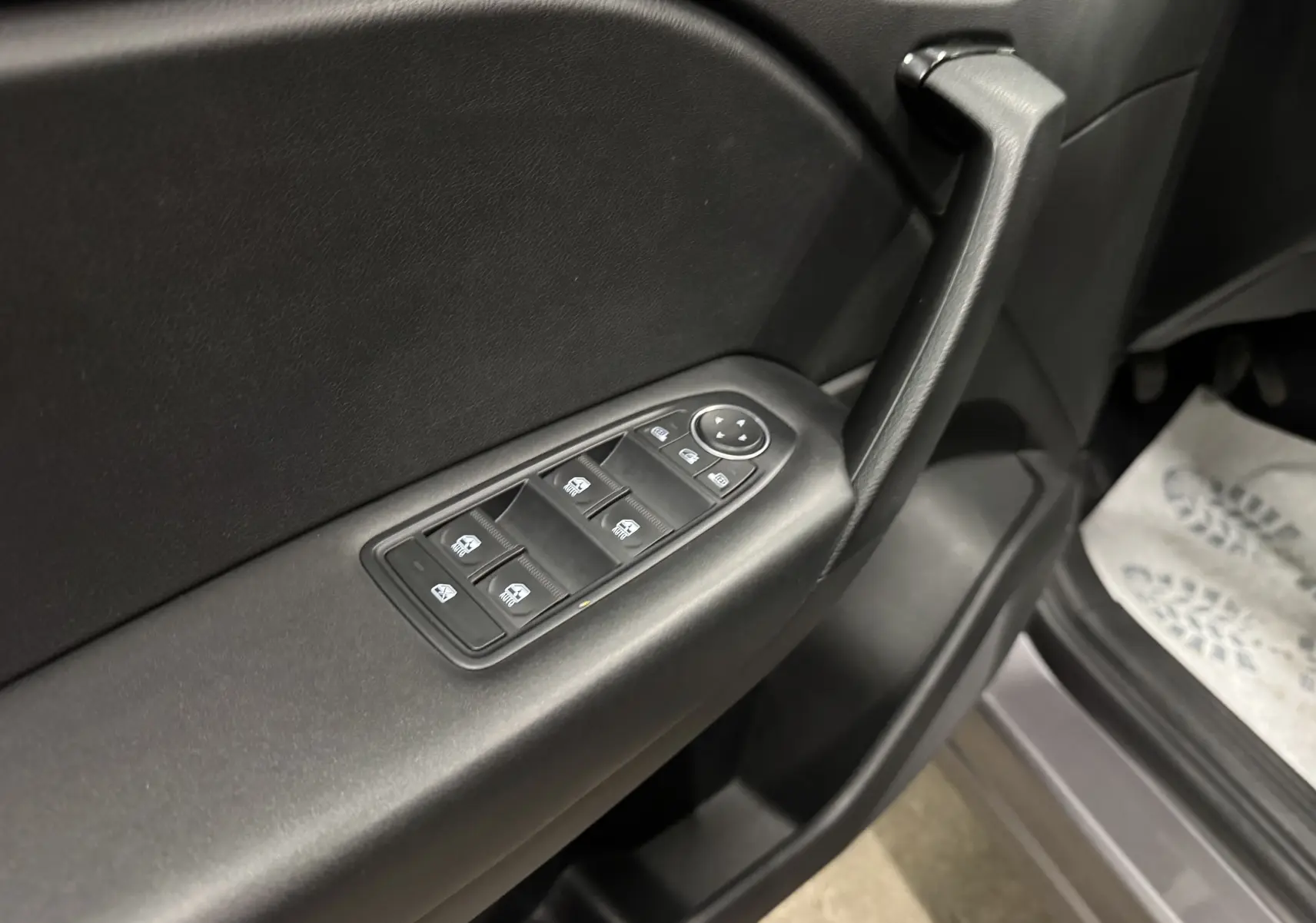 Gros plan sur la commande des vitres électriques côté conducteur d’un Renault Captur gris foncé avec intérieur noir.