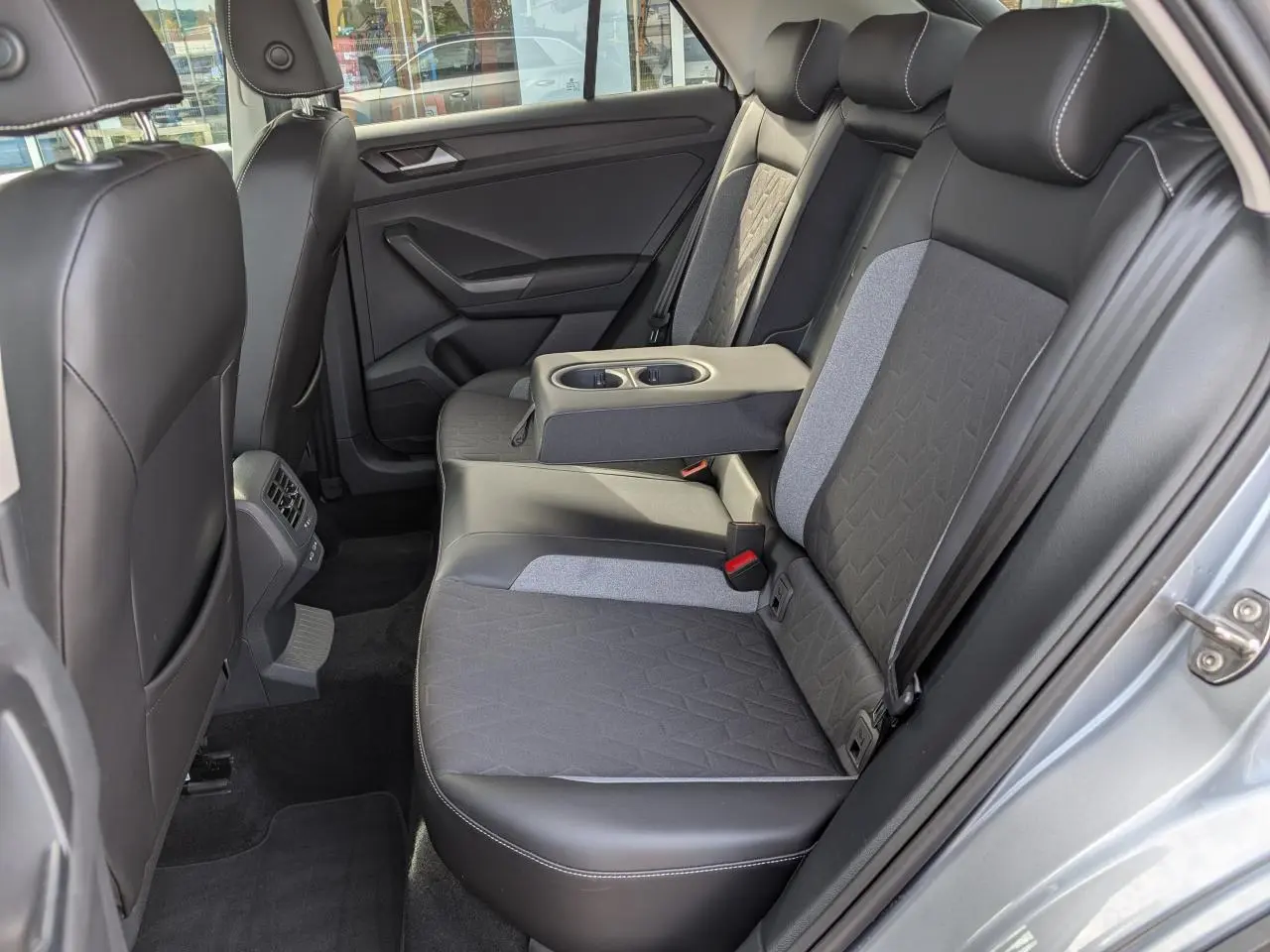 Vue côté droit de la banquette arrière gris foncé et tissu clair du Volkswagen T-Roc 2025 avec accoudoir central déployé.